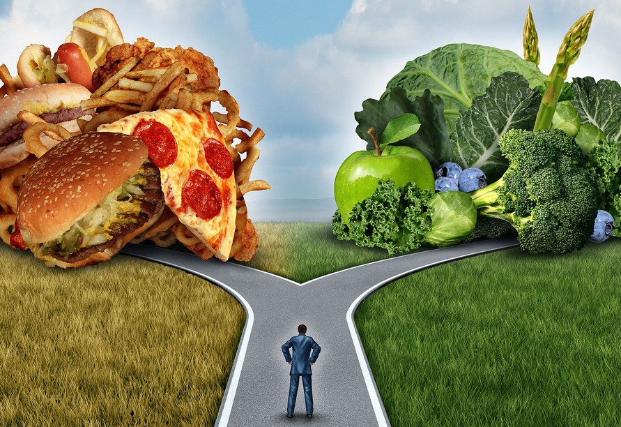 Diet decision concept and nutrition choices dilemma between healthy good fresh fruit and vegetables or greasy cholesterol rich fast food with a man on a crossroad 